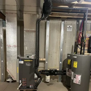 Basement HVAC area with a furnace, water heater, and copper piping connected to ducts and metal framing in the background.